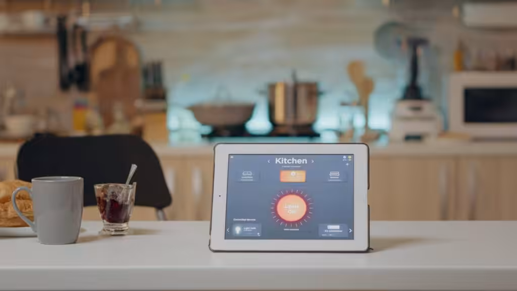 A tablet displaying intelligent software, placed on a kitchen table, surrounded by a modern kitchen setting.