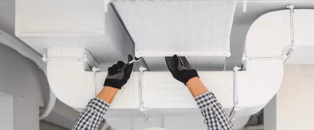 A ventilation cleaning specialist repairing an HVAC system in an industrial setting.