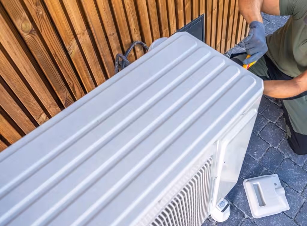Technician repairing an air conditioning unit with various tools, showcasing skilled HVAC work.