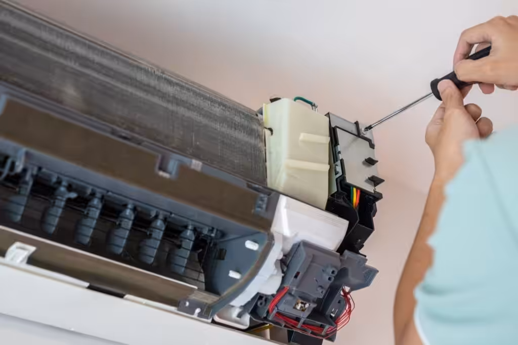 A man repairing an air conditioner, showcasing his skills as an electrician in a residential setting.