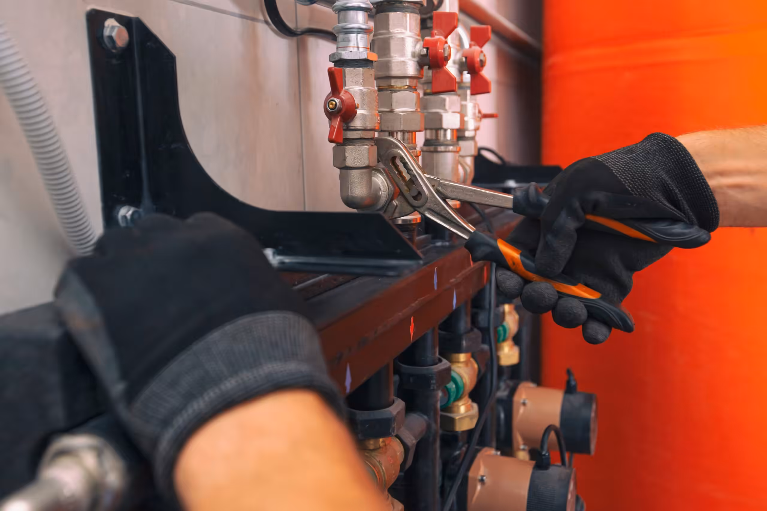 A plumber tightening a nut on a pipe within a heating system, showcasing essential maintenance work.