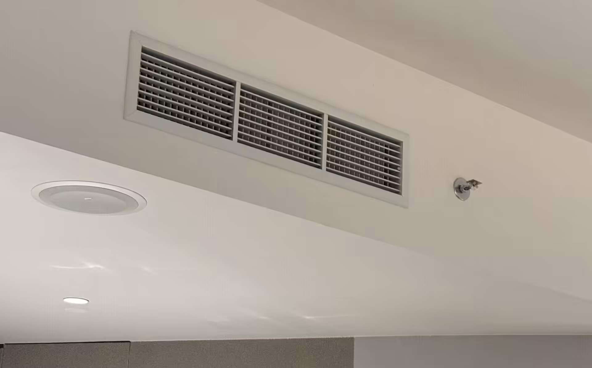 A ceiling-mounted cassette air conditioner and a modern lamp light in a stylish indoor setting.
