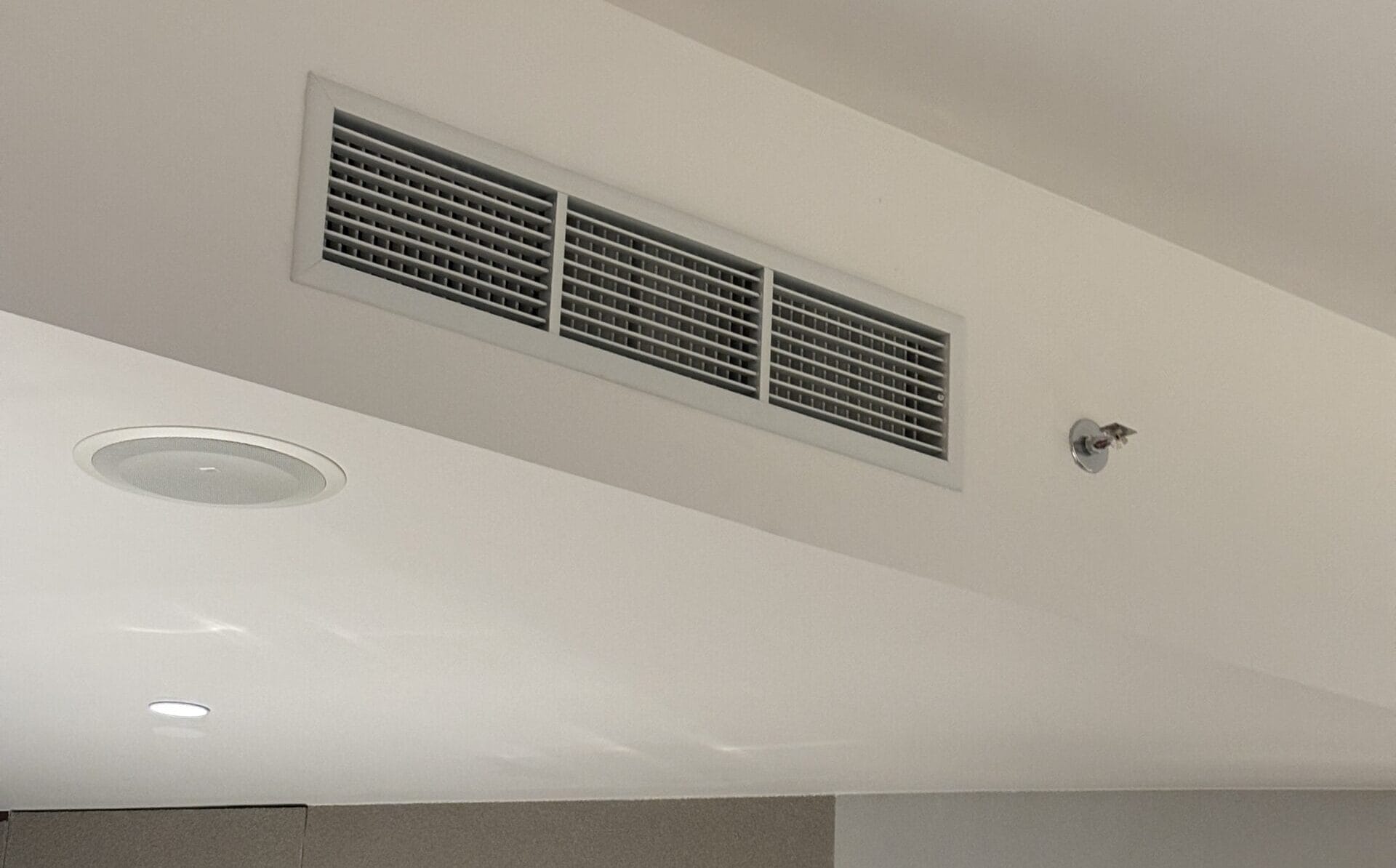 A ceiling-mounted cassette air conditioner and a modern lamp light in a stylish indoor setting.