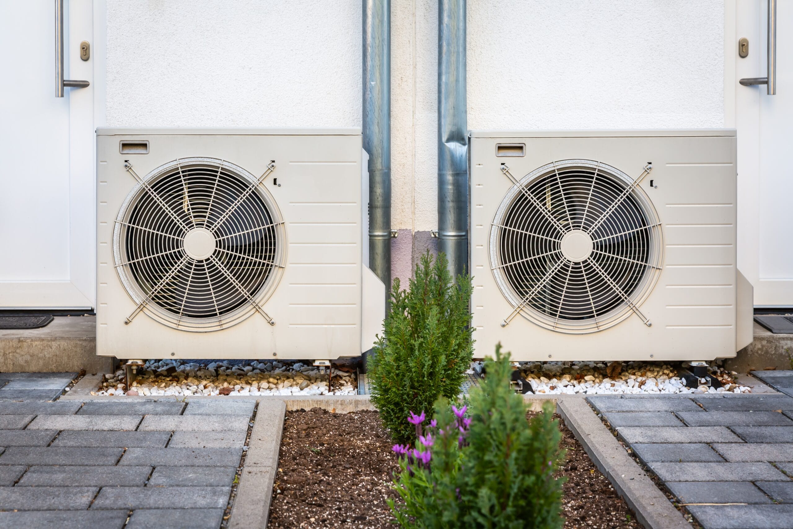 Two air source heat pumps installed outside a modern building, showcasing energy-efficient heating solutions.